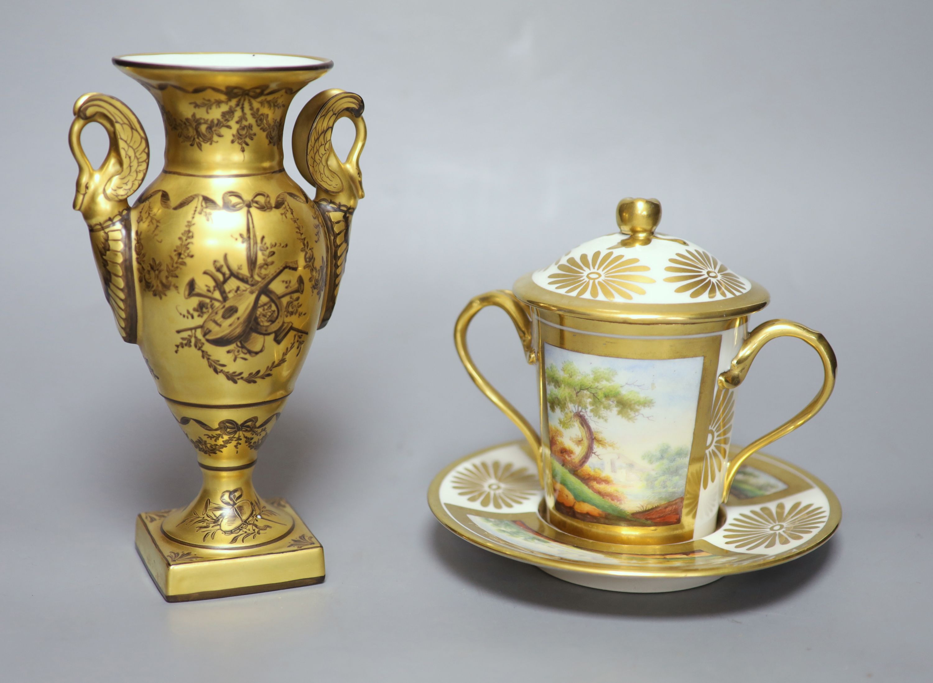 A 19th century Paris porcelain two handled chocolate cup, cover and stand painted with two landscapes in gilt panels to both the cup an